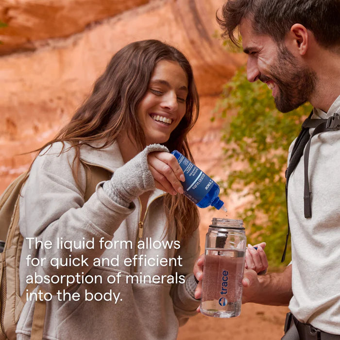 Two people outdoors with a focus on a bottle of liquid supplement.