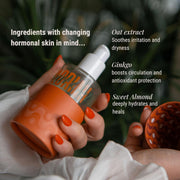 Hand holding a bottle labeled 'Nourish' with text about skincare ingredients on a blurred natural background
