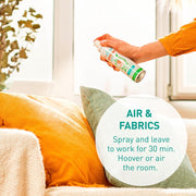 Hand spraying Puressentiel air mist in a living room.