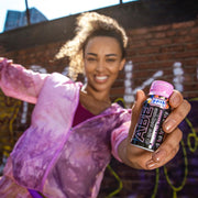 Woman holding a bottle of Abe juice in front of a brick wall.