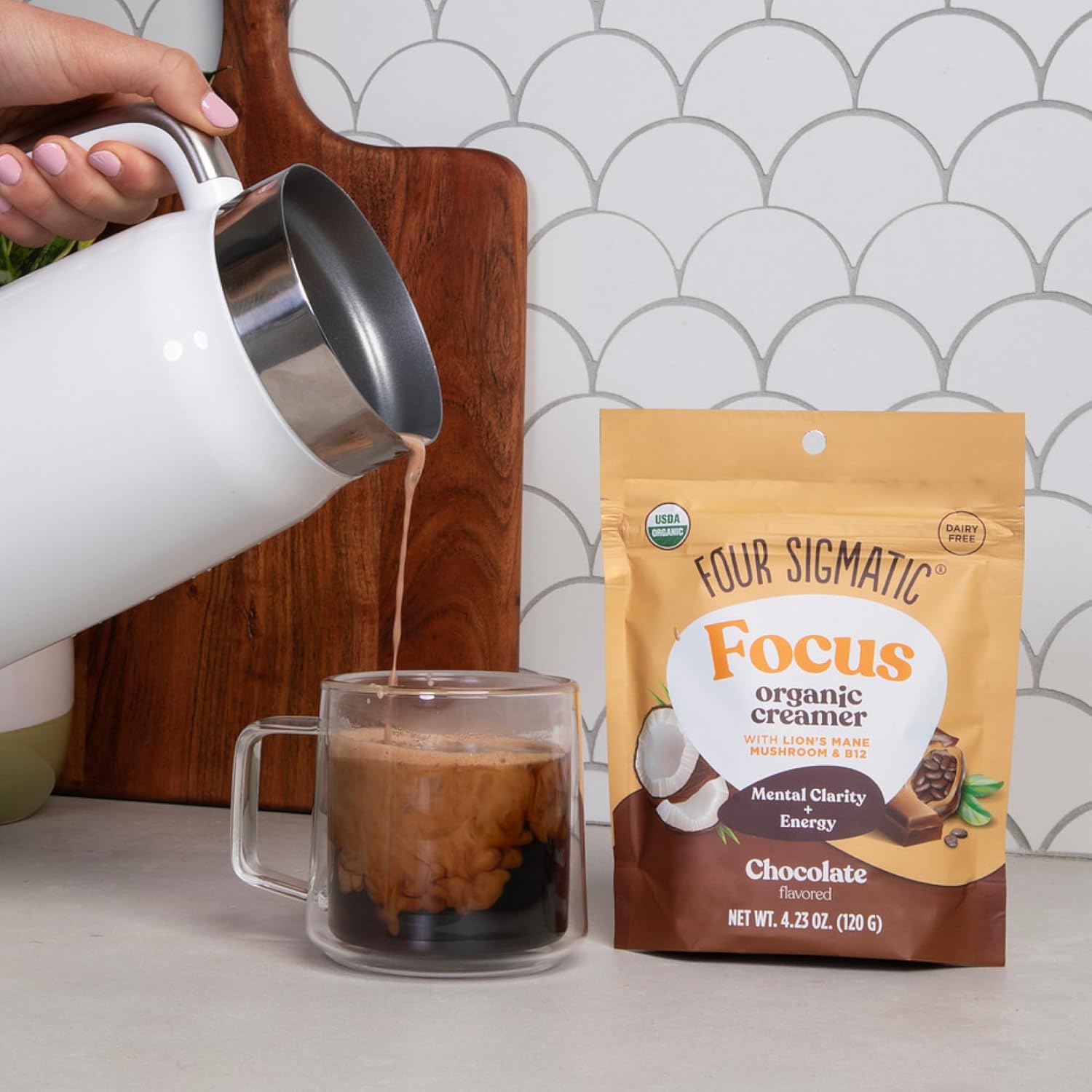Person pouring coffee into a mug with a Four Sigmatic Focus Organic Creamer packet on a kitchen counter.