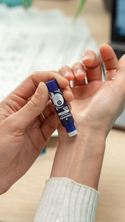 Hand applying Puressentiel roll-on to wrist for soothing massage.