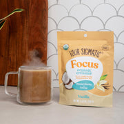 Four Sigmatic Focus Organic Creamer package next to a steaming mug of coffee.