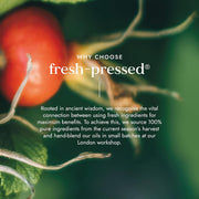Red fruit with green leaves and text about fresh-pressed products on a dark background