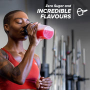 Woman in red sports bra drinking a pink supplement shake in a gym setting with text about zero sugar and incredible flavors.