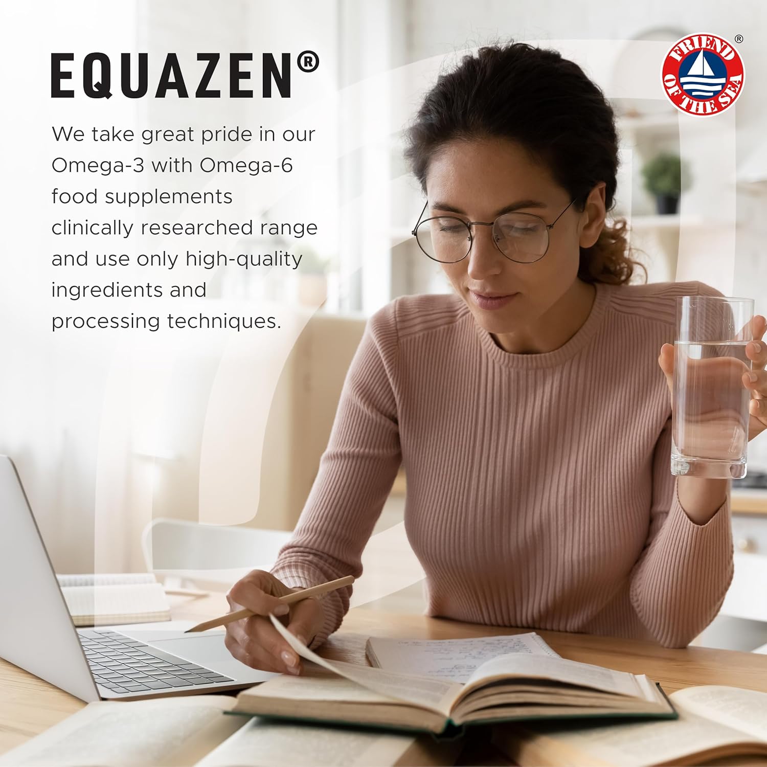 Woman sitting at a desk with a laptop and notebook, holding a glass of water, with Equazen branding in the background.