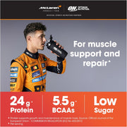 Person in racing suit holding a supplement container with McLaren and Optimum Nutrition branding.