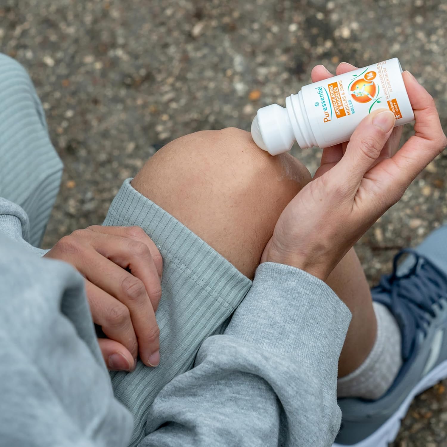 Hand holding Puressentiel roll-on applying to knee.