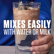 Glass of a brown liquid with a spoon, held by a hand, against a blue background with text 'Mixes Easily with Water or Milk'.