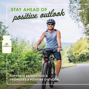 Man riding a bike on a road with trees and mountains in the background, promoting a positive outlook.