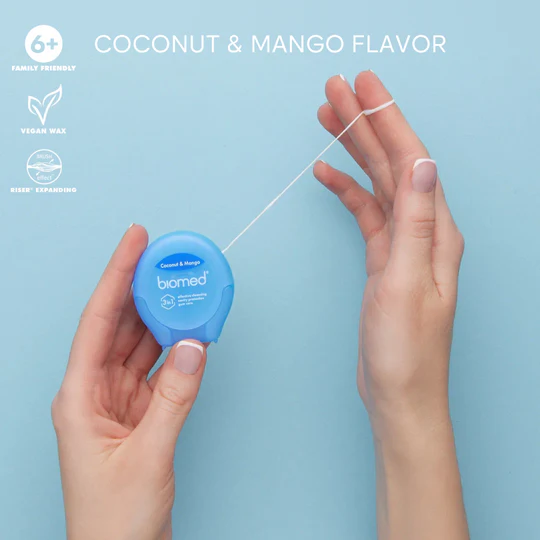 Close-up of BIOMED Coconut and Mango flavoredfloss stretched between fingers.