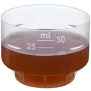 Measuring cup with Floradix Saludynam liquid beside the bottle.