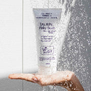 Hand holding a bottle of 'Dry, Itchy Flaky Scalp' treatment under running water.