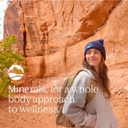 Woman standing in front of a red rock formation with text about minerals for wellness.