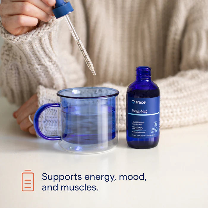 Person pouring liquid from a dropper into a blue mug with a bottle labeled 'trace' nearby.