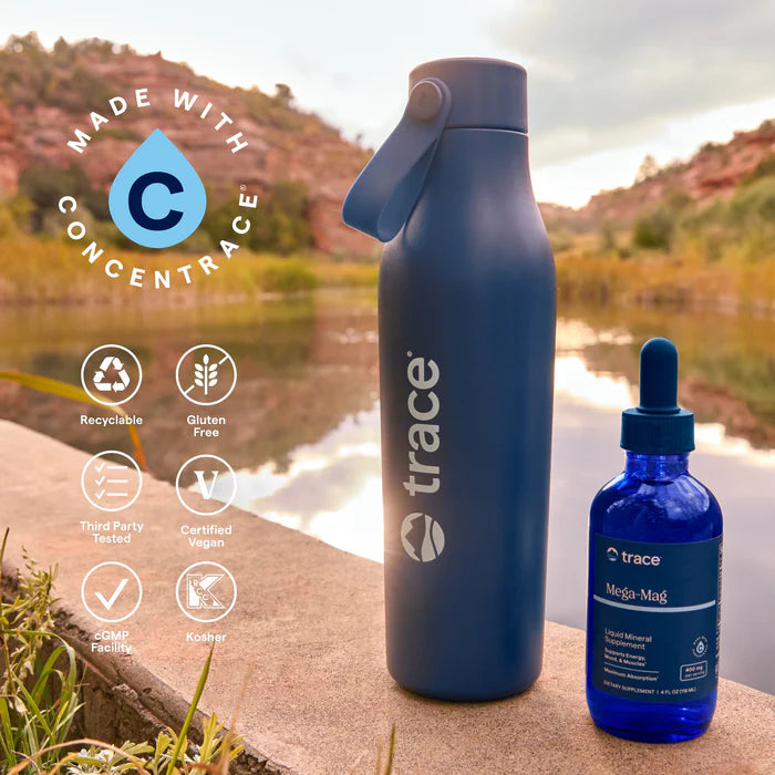 Blue water bottle and dropper bottle with 'trace' branding by a lake.