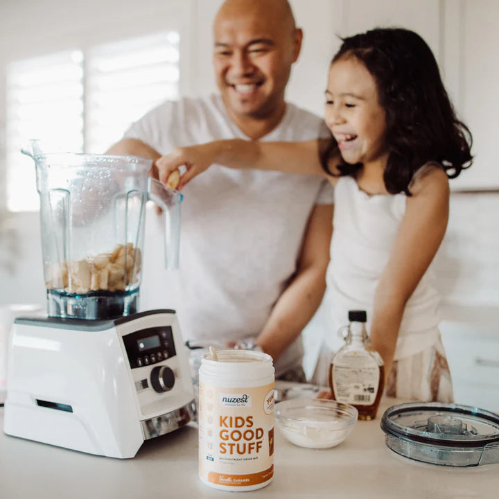 Scooping Kids Good Stuff powder into a child's cup with milk.