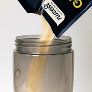A sachet of Nuzest protein powder being mixed in a shaker bottle.