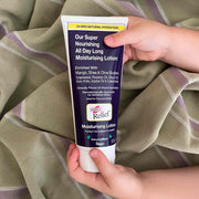 Hand holding a tube of moisturizing lotion with a checkered fabric background