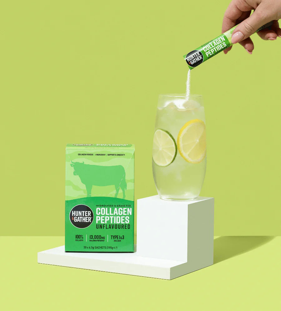 Person adding a collagen peptides stick pack to a glass of lemonade with a green background