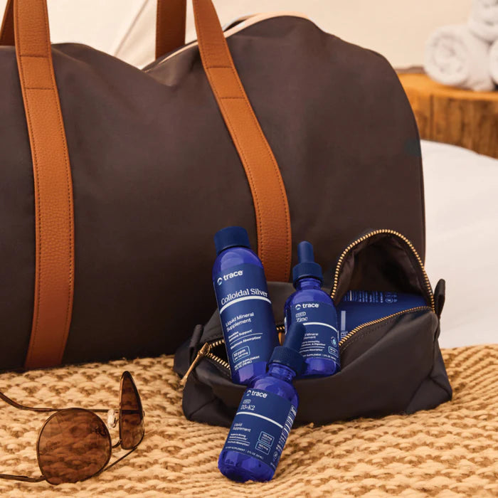 Blue bottles with a brand logo on a brown duffel bag on a textured surface.