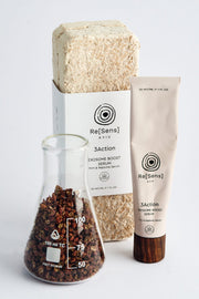 Skincare products including a tube, a glass container with brown substance, and a bar of soap on a white background.
