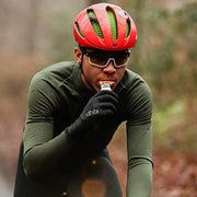 Person consuming SIS Orange energy gel from sachet during activity.