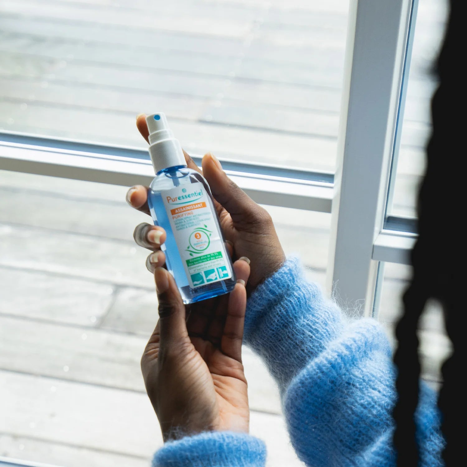 Hand spraying Puressentiel lotion for cleansing.