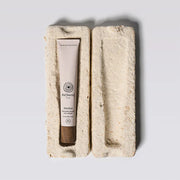 Skincare tube in a natural stone holder on a light gray background